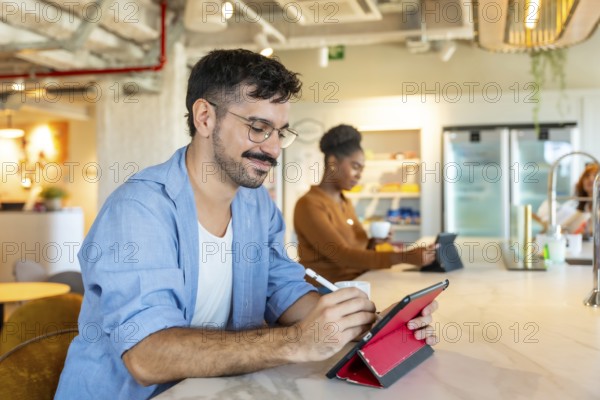 Diverse individuals making notes on a digital tablet and drinking coffee in a modern coworking