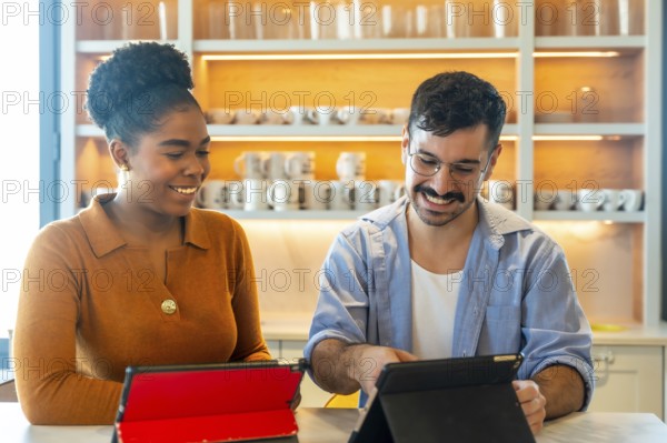 Diverse colleagues smiling and collaborating over tablets in a modern office pantry, sharing ideas