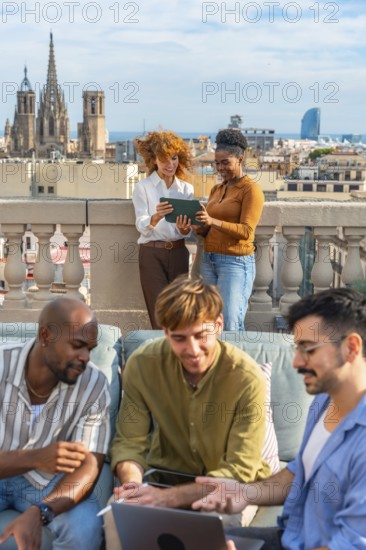 Diverse colleagues are brainstorming and working together with a laptop and tablet on a rooftop,