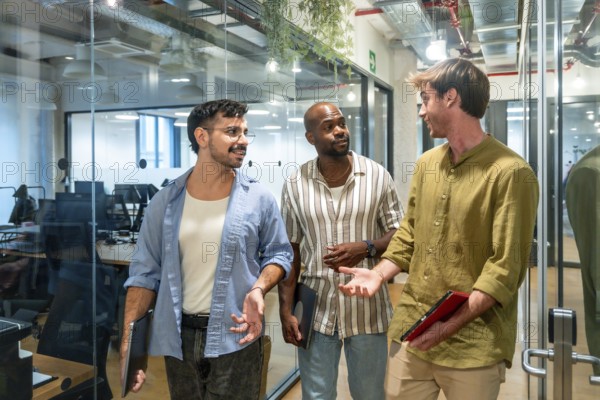 Diverse group of male colleagues engaging in a friendly discussion while walking through a modern
