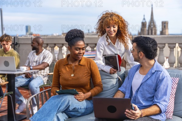Diverse business professionals collaborating and networking on a barcelona rooftop terrace, using