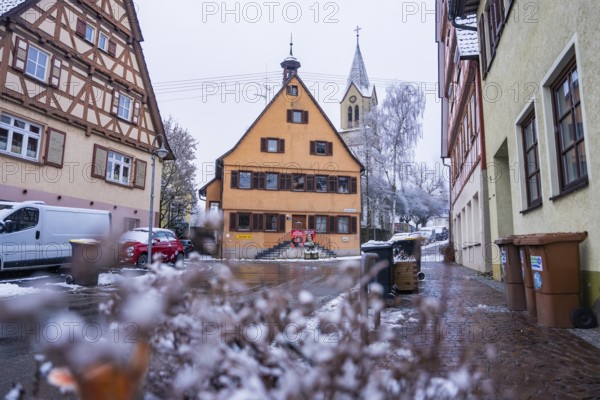Snowy village road with traditional architecture and church in the background, Gechingen, Calw