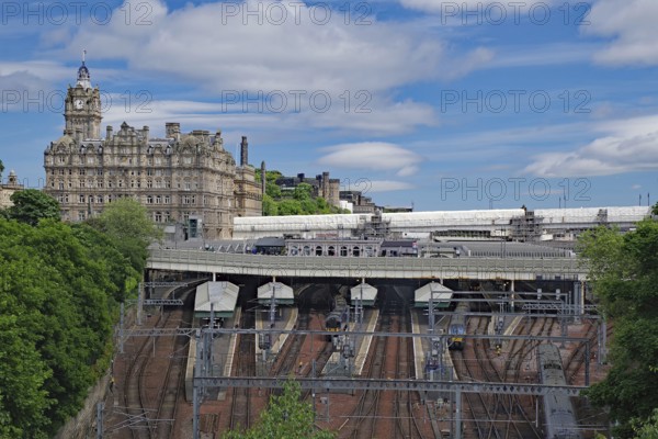 A train station with railroad tracks and an imposing building in the background, Waverley Station,