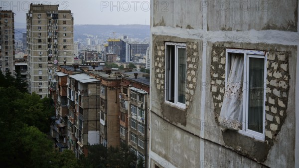 Old apartment blocks with worn facades against a city backdrop, nostalgic curtain blowing out the