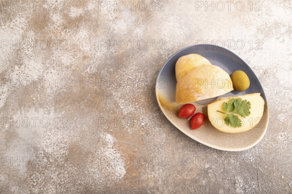 Smoked Mozzarella cheese, with tomatoes and olives on brown concrete background, top view, flat