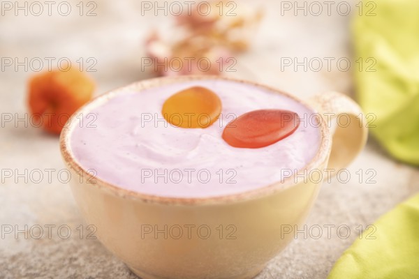 Purple Yogurt, with jelly candy on brown concrete background and green textile, side view, close