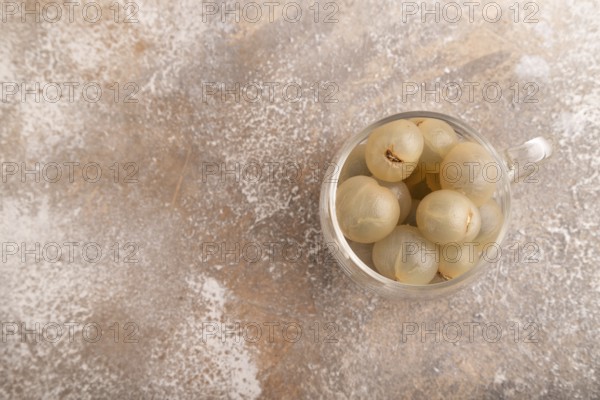 Ripe peeled Longan in glass on brown concrete background, top view, flat lay, copy space,