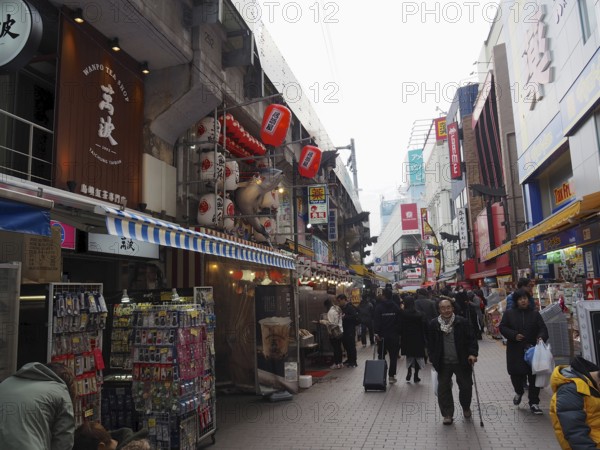 Bustling shopping street with shops and people decorated with red lanterns and signs, Ameyoko