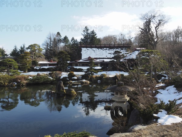 Snowy Japanese garden with small ponds and traditional buildings in the background, Oshino Hakkai,