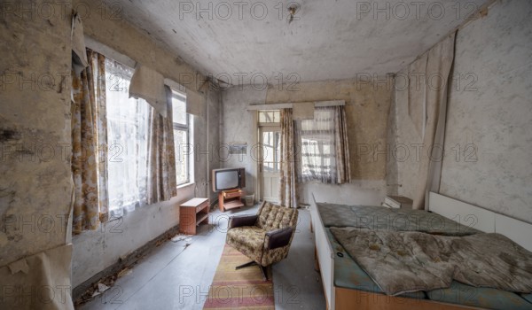 Abandoned hotel room with bed, armchair and television in a dilapidated hotel, Lost Place,