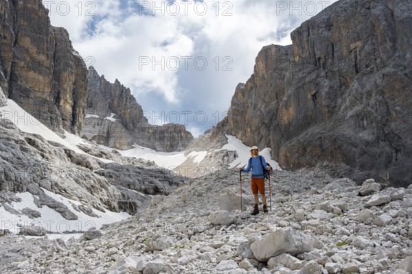 Hikers in a gap, Sentiero Brentari in front of rock faces, Brenta Mountains, Brenta-Adamello