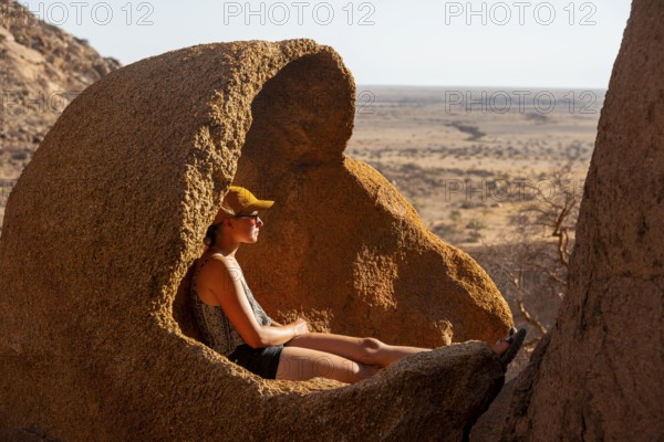 Person sitting relaxing in a natural rock area and enjoying the view of the desert, Spitzkoppe,