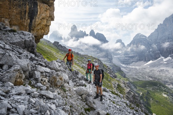 Climbers on a hiking trail, rocky mountain landscape with fog, Via Ferrata SOSAT via ferrata,