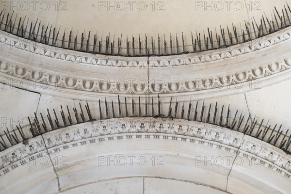 Stone arches with decorative ornaments and long metal spikes to repel pigeons, Royal Academy of
