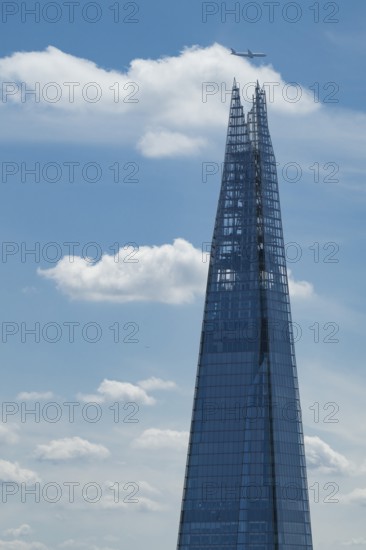 View from the Sky Garden of the modern glass skyscraper The Shard over which an airplane flies,