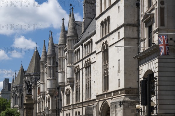 Royal Courts of Justice, neo-Gothic architecture with towers and British flag under blue sky,