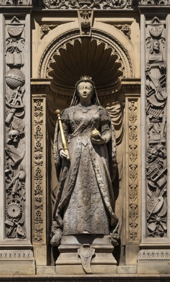 Queen statue with scepter and orb surrounded by decorative elements depicting Queen Victoria,