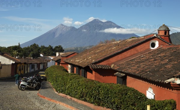 Traditional houses in a cobblestone alley with the Fuego volcano in the back, Old Town, Antigua,