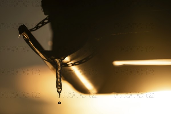 A drop of water comes off an icicle on a gutter in warm sunlight, back light, winter, Korpoström,