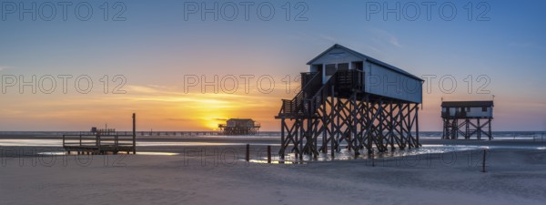 Stilt houses at low tide on the beach at sunset, St. Peter-Ording, Schleswig-Holstein Wadden Sea