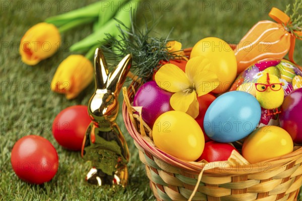 A basket with colorful eggs, flowers and Easter decoration in a meadow