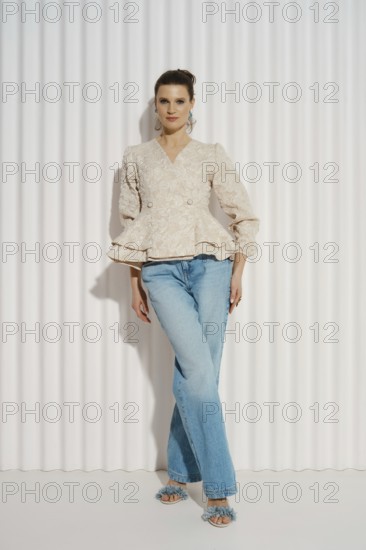 A model stands confidently in a well-fitted top and jeans. She has her left hand on her hip and her