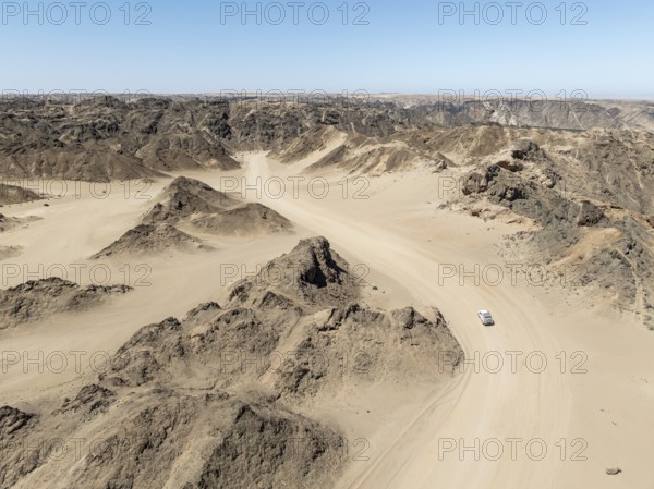 Aerial view, dry barren mountains in Moon Valley, road with car, rocky landscape ridged by erosion,