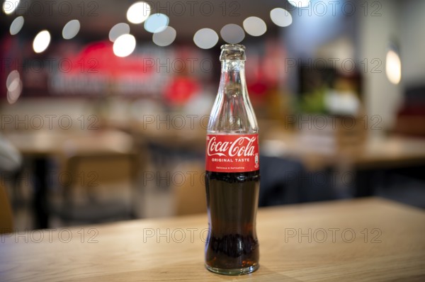 Coke, Coca-Cola, bottle, 0.3 liter, half full, half empty, standing on a table, restaurant, bar,