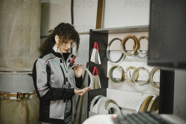 A woman stands in a workshop looking closely at a finishing edge. She is surrounded by various