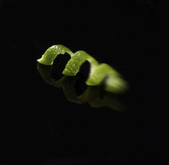 Lime zest against black background, motion blur, studio shot
