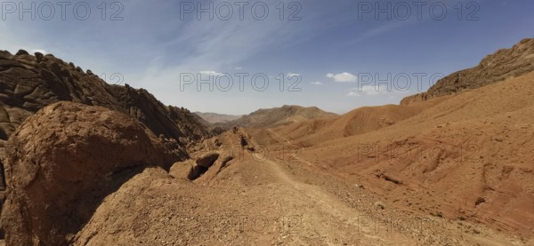 Desert hills with eroded rocks and trails under clear skies, Morocco