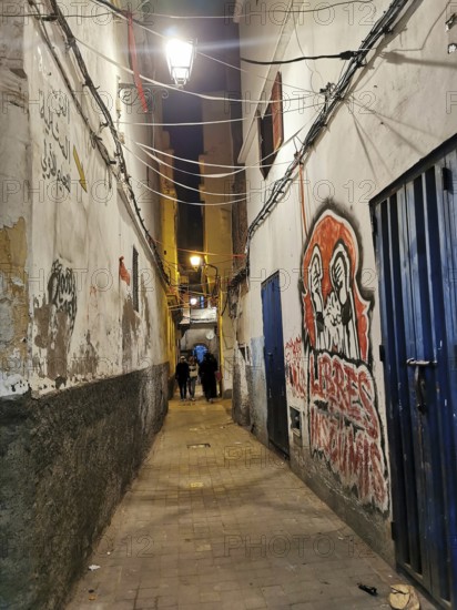 Narrow alley at night, illuminated with walls covered with graffiti and urban flair, Medina,