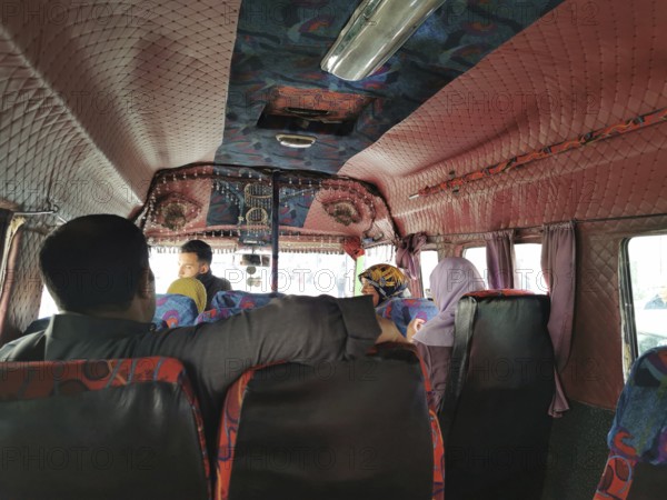 People sitting and talking in the interior of a colorful old bus, Morocco