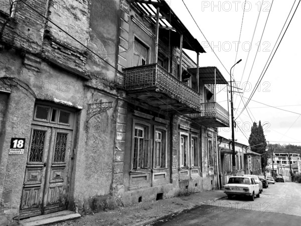 Deserted street with old, dilapidated buildings and a nostalgic parked classic car, car,