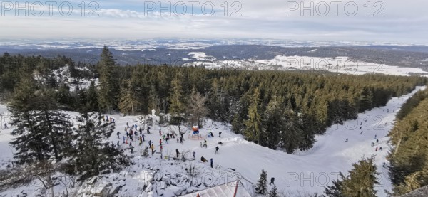 Winter landscape with snow-covered forest and people skiing, ski lift at Ochsenkopf, Fichtelgebirge