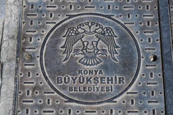 Metal manhole cover with Konya coat of arms and Turkish text, robust urban design, Gully, Konya,