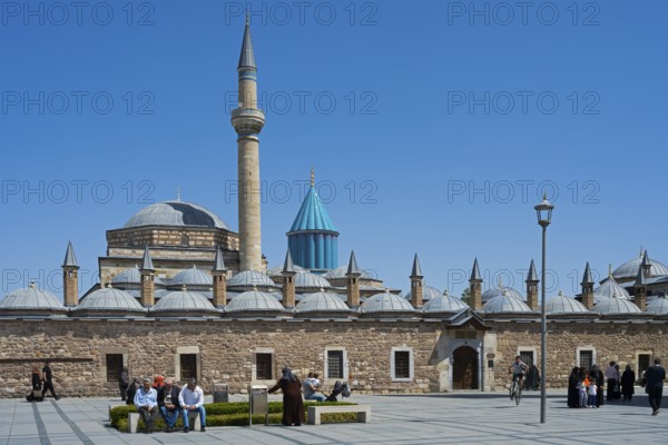 View of a large mosque with minaret and domes surrounded by people and blue sky, Mevlana Museum,