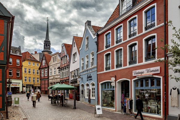 Historic street with colorful half-timbered houses and shop windows under a cloudy sky, The old
