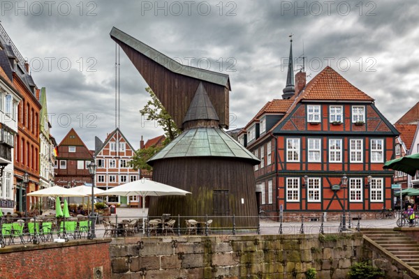 Historic timber crane building and half-timbered houses with terraces under a cloudy sky, The old
