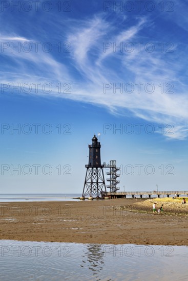 A lighthouse on the beach under a clear sky with picturesque clouds, Die Kugelbake von Cuxhaven