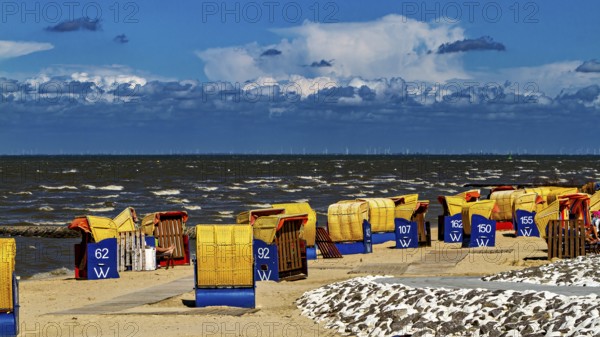 Several beach chairs along a windy beach with dramatic sky in the background, beach chairs on