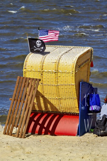 A single yellow beach chair on the beach with American and pirate flag in the wind, beach chairs on