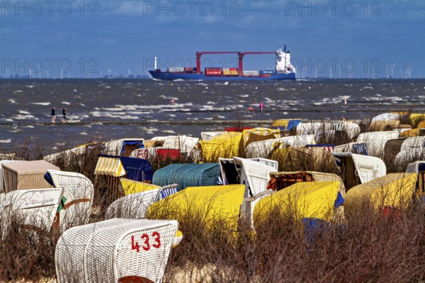 Beach chairs on the beach with a ship on the sea and wind turbines on the horizon, beach chairs on