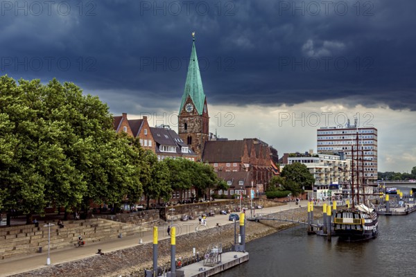 City landscape with a church, its Gothic tower and boats on the waterfront under a cloudy sky, The