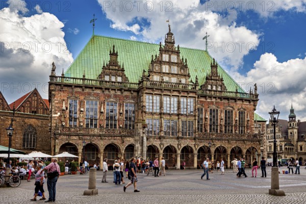 Renaissance town hall with lively hustle and bustle on the paving stone square under a cloud cover,