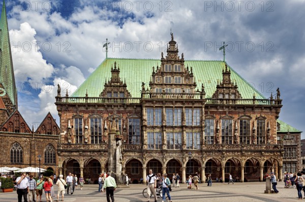 Impressive Renaissance building with green roof and statue, people walking in changeable weather,