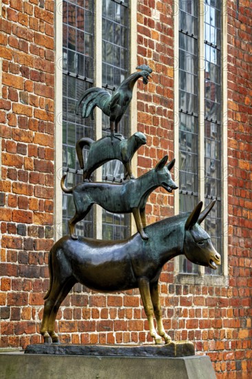 Bronze sculpture of the Bremen Town Musicians in front of a historic brick wall, The Bremen Town