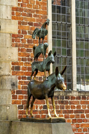 The Town Musicians of Bremen as a bronze sculpture in front of an old wall with windows, The Bremen