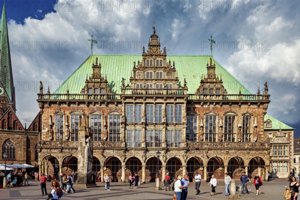 A historic Renaissance-style building on a busy market square in Bremen, under a cloudy sky, The