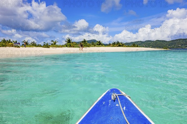 View of blue bow from small tour boat onto turquoise blue-green lagoon in front of uninhabited